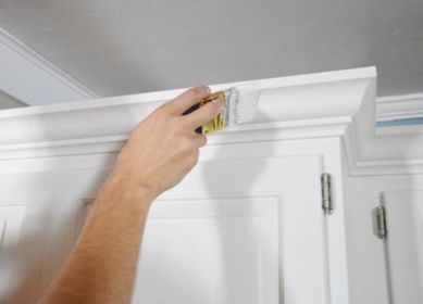 Cabinet painting and refinishing with precise brushwork on top molding