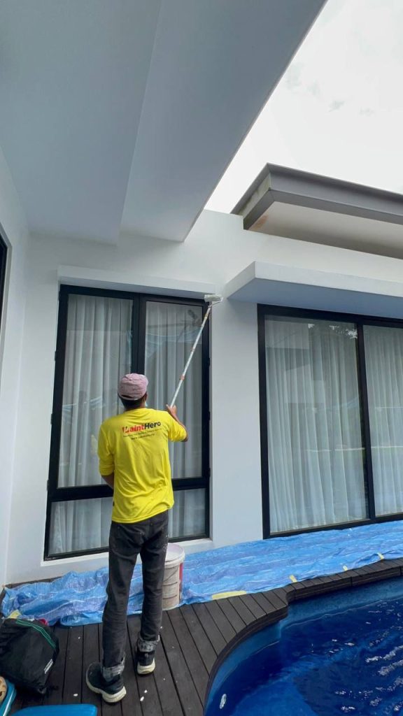 Tukang cat Painthero mengecat luar rumah tepi kolam.