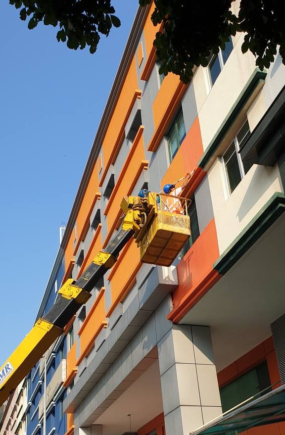 Kerja cat fasad bangunan komersial oleh Painthero menggunakan boom lift.