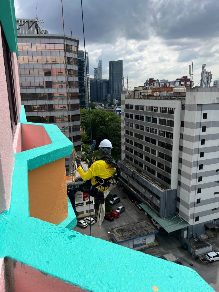 Kerja cat luar bangunan tinggi di Kuala Lumpur oleh Painthero menggunakan rope access.